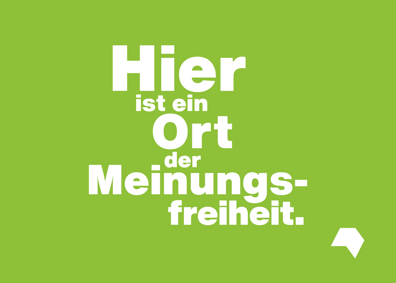 The phrase „Hier ist ein Ort der Meinungsfreiheit“ is written in white on a green surface.