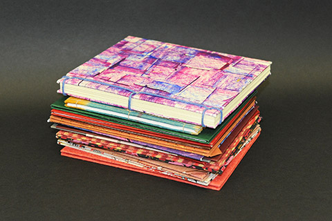 Pile of bound booklets covered with colourful patterned papers