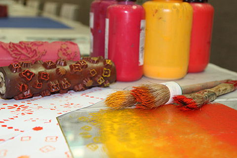 Brushes, wallpaper sample and bottles of red and yellow ink