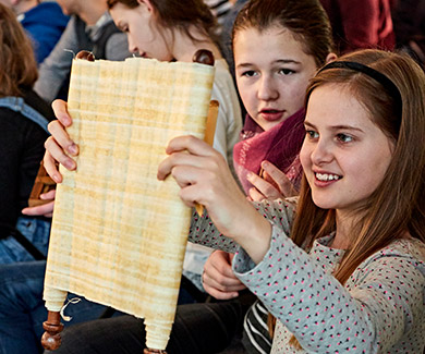 A group of girls looking at a papyrus scroll