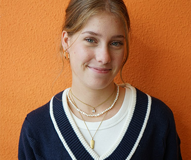 Eine Mitarbeiterin vor orangener Wand Eine Mitarbeiterin vor orangener Wand