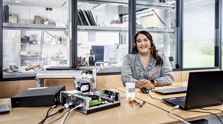 Eine Mitarbeiterin sitzt an ihrem Schreibtisch vor einem Notebook. Links daneben ein zerlegter PC. Eine Mitarbeiterin sitzt an ihrem Schreibtisch vor einem Notebook. Links daneben ein zerlegter PC.