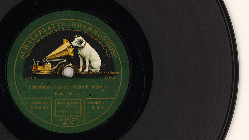 Schellackplatte „Eisenbahn - Parodie“ von Rudolf Mälzer; hergestellt von der Deutschen Grammophon Aktiengesellschaft Berlin mit der für sie typischen Fotomontage „Hund guckt in ein Trichtergrammophon“