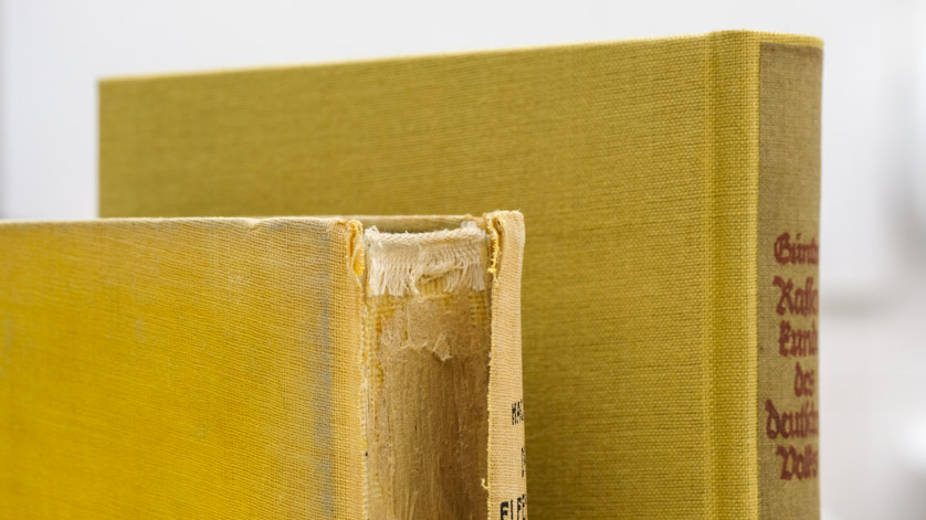 Der stark beschädigte Rücken eines Buches im Vorher-Nachher-Vergleich der Restaurierung