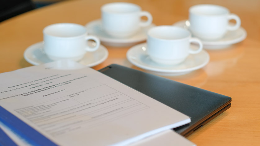 Notebook, Projektbericht und Kaffeetassen auf einem Besprechungstisch