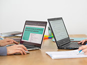 Zwei aufgeklappte Laptops auf einem Tisch. Auf einem der Bildschirme ist die Webseite DNBLab zu sehen. 