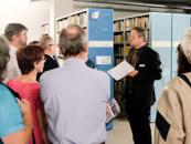 Besuchergruppe mit Bücherregalen im Hintergrund, ein Gästeführer erläutert das Magazin der Deutschen Nationalbibliothek in Frankfurt am Main
