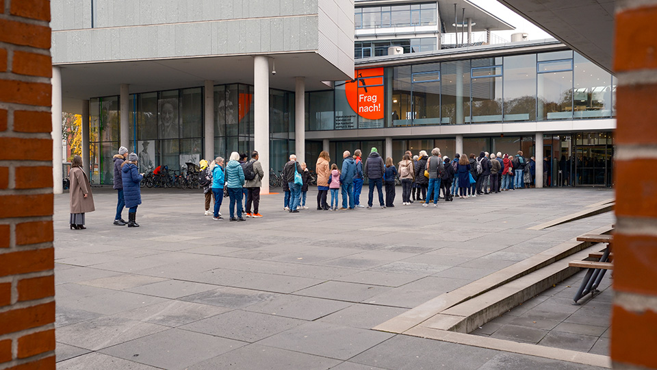 Viele Personen stehen in einer Schlange vor der Deutschen Nationalbibliothek in Frankfurt am Main