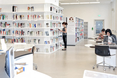 Der Lesesaal der Anne-Frank-Shoah-Bibliothek der Deutschen Nationalbibliothek in Leipzig - mit Arbeitstischen, Computerbildschirmen und gefüllten Bücherregalen
