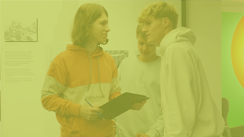 Drei Jugendliche in der Ausstellung des Deutschen Exilarchivs, die sich unterhalten. Das Bild ist in Hellgrün eingefärbt. Drei Jugendliche in der Ausstellung des Deutschen Exilarchivs, die sich unterhalten. Das Bild ist in Hellgrün eingefärbt.