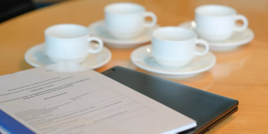 Notebook, Projektbericht und Kaffeetassen auf einem Besprechungstisch