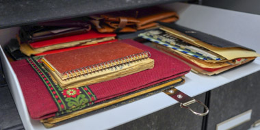 Eine geöffnete Archivschachtel aus dem Nachlass von Clementine Zernik. Zu sehen sind einige Notizhefte mit besonders schönen Einbänden, in die unter anderem Briefe eingelegt sind. Eine geöffnete Archivschachtel aus dem Nachlass von Clementine Zernik. Zu sehen sind einige Notizhefte mit besonders schönen Einbänden, in die unter anderem Briefe eingelegt sind.