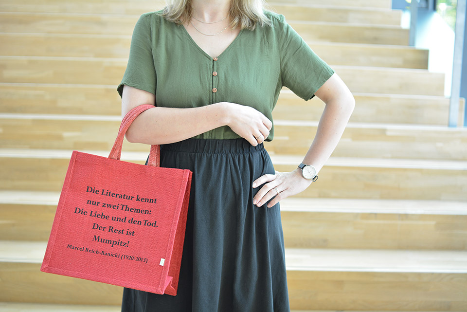Eine Messebesucherin mit einer roten Buchtasche am Arm – darauf gedruckt ein Zitat Marcel Reich-Ranickis
