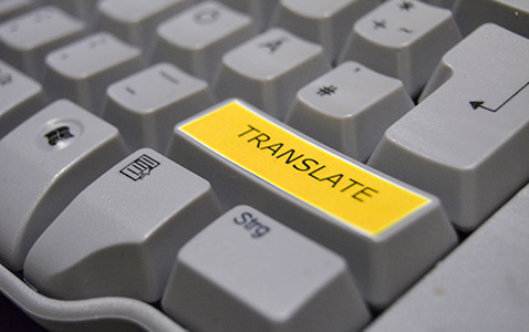 Eine Computertastatur, bei der  eine der hervorgehobenen Tasten mit einer "Übersetzen"-Funktion belegt worden ist. Hervorgehoben durch das Wort "Translate" auf gelbem Hintergrund.