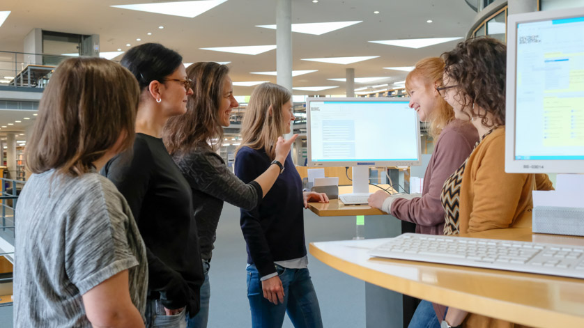 Group of users standing around a catalogue screen during a user introduction in the reading room