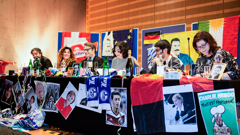 The “set” of the “Hate Poetry” event. The Hate Poetry team is sitting round a table brightly decorated with posters, photographs, flags, football scarves and garlands.