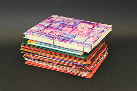 Pile of bound booklets covered with colourful patterned papers Pile of bound booklets covered with colourful patterned papers