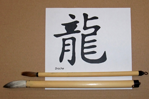 Two calligraphy brushes lying on a piece of white paper on which Chinese characters have been painted Two calligraphy brushes lying on a piece of white paper on which Chinese characters have been painted