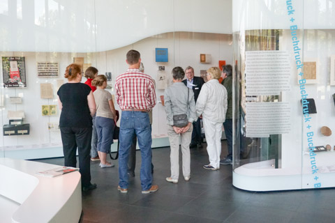 Gästegruppe vor Vitrinen der Ausstellung „Zeichen - Bücher Netze“ des Deutschen Buch und Schriftmuseums in Leipzig