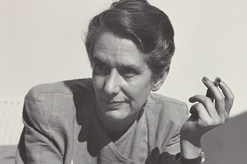 The black-and-white photo shows Erika Mann at the age of 43. She is looking toward the right and holding a cigarette between the fingers of her left hand.