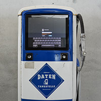 A blue and white fuel pump with an integrated screen positioned in front of a grey wall