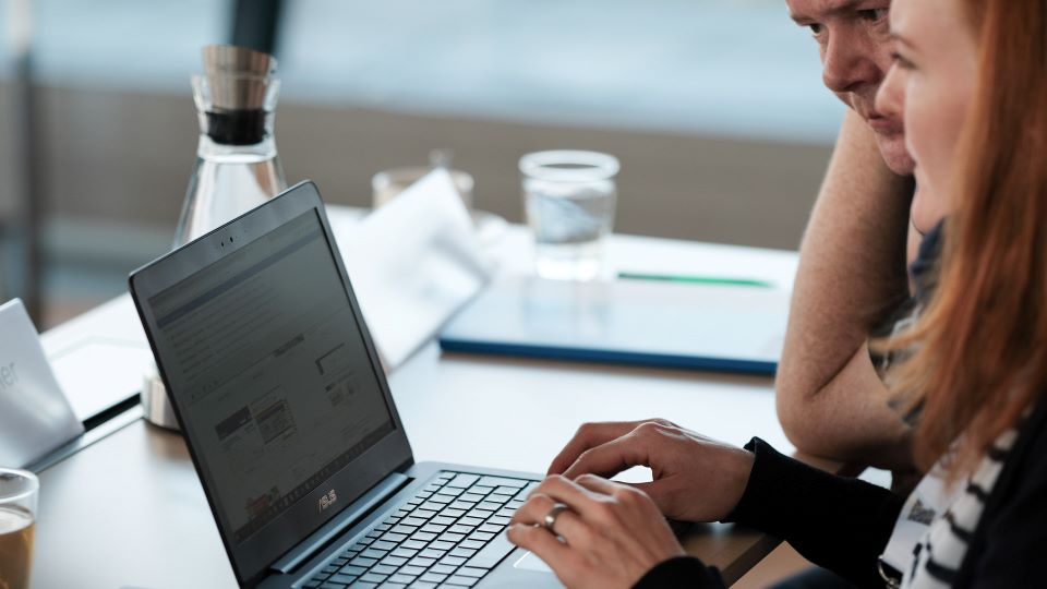 A woman writes on a laptop, a man watches the screen with interest.. A woman writes on a laptop, a man watches the screen with interest..