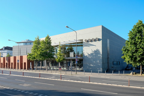Kongresszentrum der Deutschen Nationalbibliothek an der Frankfurter Adickesallee. Betonkubus mit Glasfront und Bäumen, seitlich die mäandernde Backsteinmauer von Peer Kirkeby